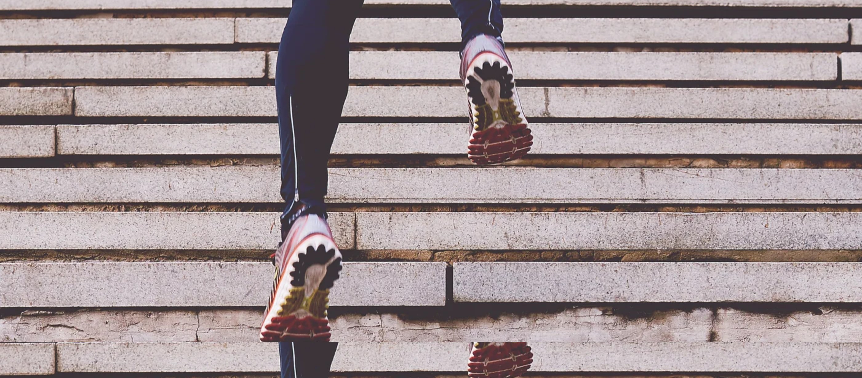A runner's legs climbing stone steps