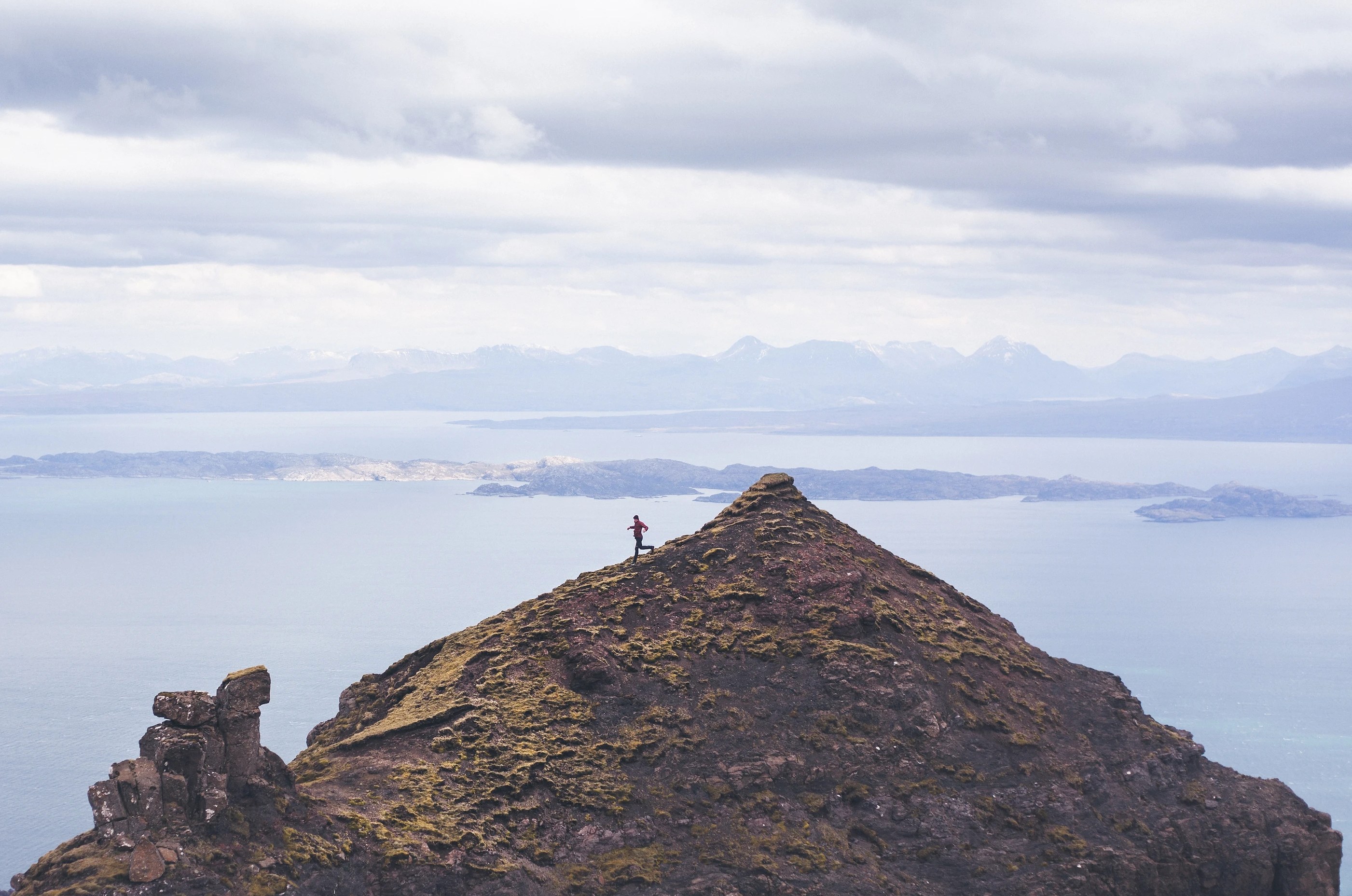 A runner on top of a rocky peak above the sea